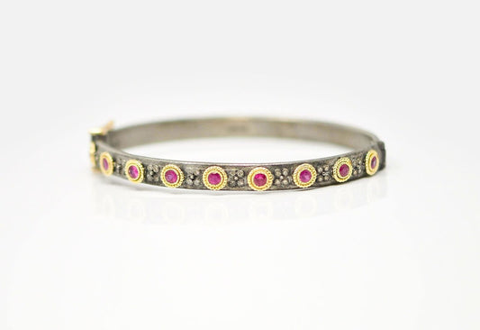 18k yellow gold and grey sterling silver bracelet with round ruby stations and champagne diamonds. Bracelet Size 0